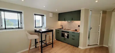 a kitchen with green cabinets and a small table at Morgensolen in Bergen