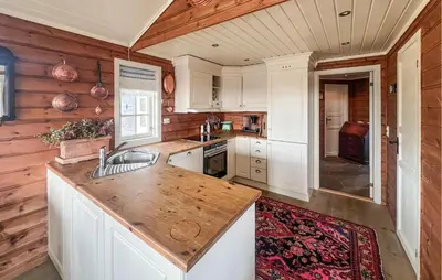 a kitchen with white cabinets and a wooden wall at Stunning Home In Etnedal With Sauna in Etnedal