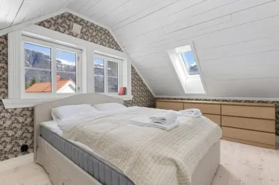 a bedroom with a bed in a attic with windows at Tømmerhuset på Brekketunet in Stryn