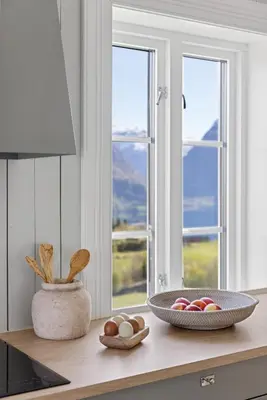 a kitchen counter with two windows and a bowl of eggs at Tømmerhuset på Brekketunet in Stryn