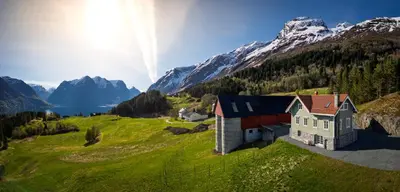 a house on a hill with mountains in the background at Tømmerhuset på Brekketunet in Stryn
