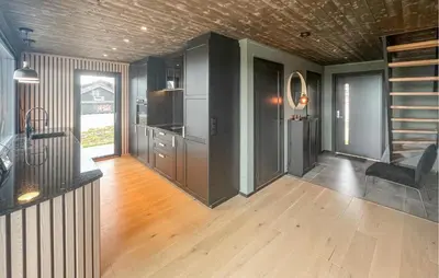a kitchen with black cabinets and a wooden floor at Amazing Home In Løten in Løten