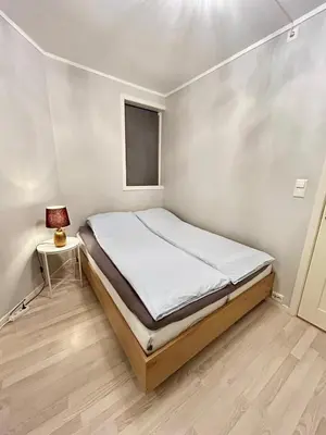 a small bedroom with a bed and a lamp at Apartment in the Heart of Ålesund in Ålesund