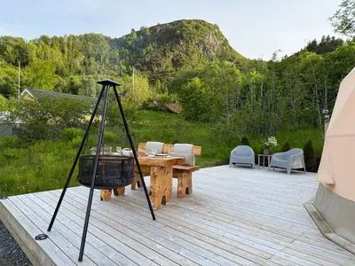 a wooden deck with a table and chairs and a basket at Idyllisk overnatting i dome ved sandstrand in Langenes