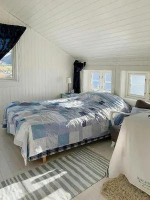 a bedroom with a bed and two windows at Coastal Cabin With Panoramic Views In Høvikstranda