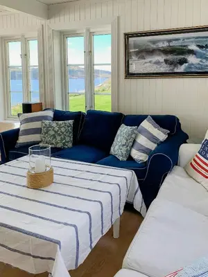 a living room with a blue couch and windows at Coastal Cabin With Panoramic Views In Høvikstranda