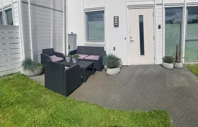 a patio with two chairs and a table and potted plants at Rom i nyere rekkehus nord i Haugesund in Haugesund