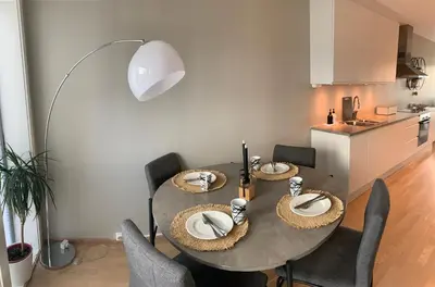 a dining room with a table and chairs and a kitchen at Rom i nyere rekkehus nord i Haugesund in Haugesund