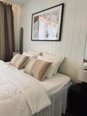 a white bed with pillows and a picture on the wall at Bo i Bergens eldste smau på Nøstet - sentralt og rolig in Bergen