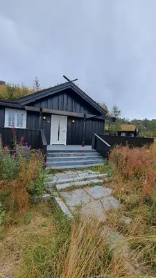 a black house with a white door and a porch at Cozy Cottage in Rauland Vierli in Torvetjørn