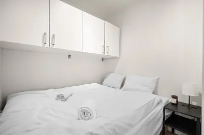 a bedroom with a white bed with white cabinets at Bergen Beds Apartment I Right Behind Bryggen! in Bergen