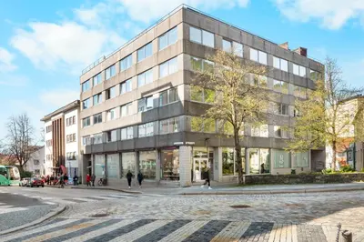 a building on a street with people walking in front of it at Bergen Beds Apartment I Right Behind Bryggen! in Bergen