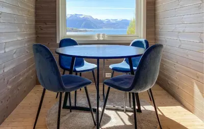 a table and four chairs in a room with a window at Knausen in Ørsta