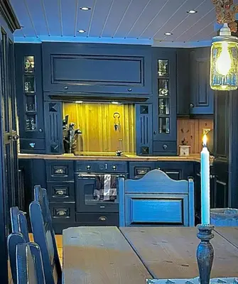 a kitchen with blue cabinets and a table and chairs at Family-Friendly Mountain Cabin At Haglebu in Haglebu