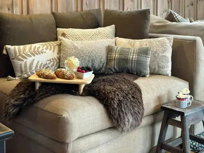 a couch with pillows and a tray of food on it at Family-Friendly Mountain Cabin At Haglebu in Haglebu