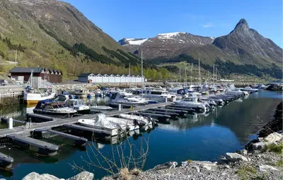 a bunch of boats docked in a harbor with mountains at 2 Bedroom Lovely Home In Ørsta in Ørsta