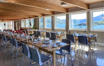a row of tables and chairs in a room with windows at Awesome Home In Ørsta in Ørsta