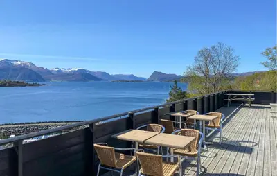 a deck with tables and chairs and a view of the water at Awesome Home In Ørsta in Ørsta