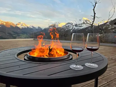 a table with two wine glasses and a fire pit at Mountain View Lodge in Stranda