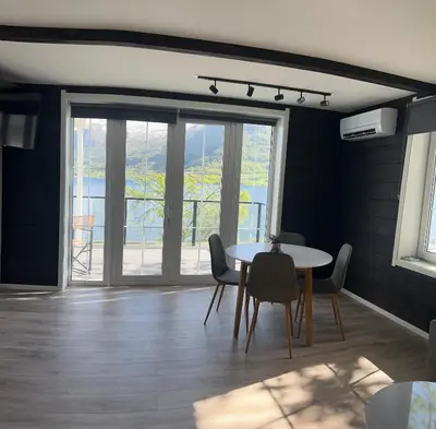 a dining room with a table and chairs and a window at Husslåttene apartments 2 in Skei