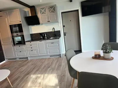 a kitchen with white cabinets and a table and chairs at Husslåttene apartments 2 in Skei