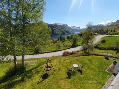 a backyard with two picnic tables and a view of a river at Leilighet i Røldal in Håra