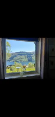 a window with a view of a picnic table and a lake at Leilighet i Røldal in Håra