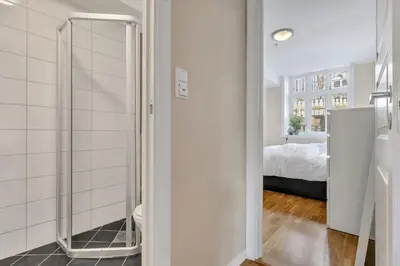 a bathroom with a walk in shower next to a bedroom at Central Charm in Bergen