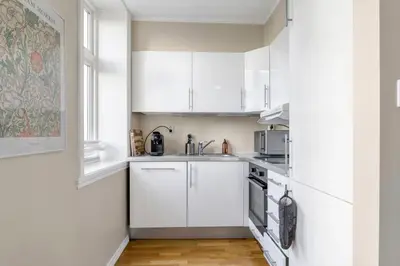 a white kitchen with white cabinets and a sink at Central Charm in Bergen