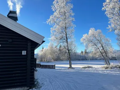 a building with a snow covered field and trees at Log Cabin With Mountain View in Beitostøl
