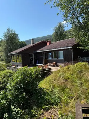 a house on a hill with a yard at 4 bedroom room House in Beautiful Strandebarm in Kvam