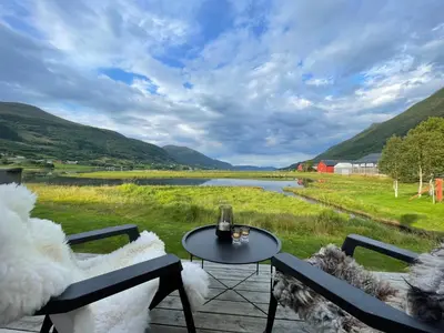 a patio with two chairs and a table and a lake at Strandhus i idylliske omgivelser in Batnfjordsøra