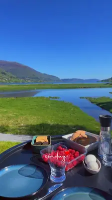 a table with a tray of food on a table with a lake at Strandhus i idylliske omgivelser in Batnfjordsøra