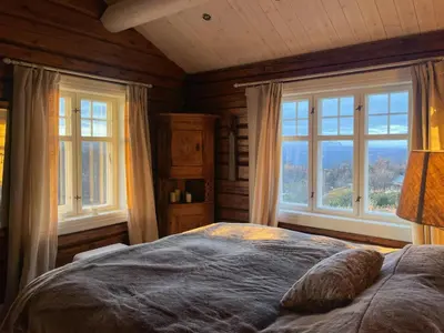 a bedroom with a large bed with windows in it at Charming Log Cabin With Modern Luxury in Dagali
