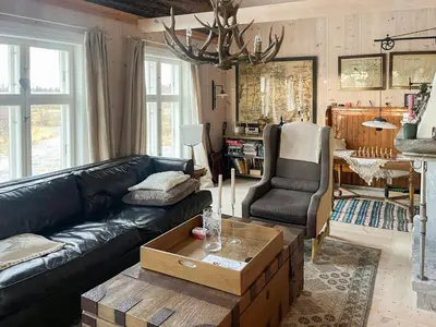 a living room with a black leather couch and a table at Charming Log Cabin With Modern Luxury in Dagali
