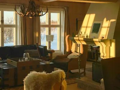 a living room with a dog standing in front of a table at Charming Log Cabin With Modern Luxury in Dagali