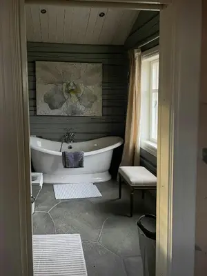 a bathroom with a tub and a chair and a window at Charming Log Cabin With Modern Luxury in Dagali