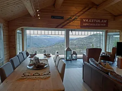 a dining room with a large wooden table and chairs at Mountain villa with amazing view of Hardangervidda! in Nørdstebø