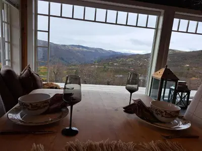 a table with two wine glasses and a table with a view at Mountain villa with amazing view of Hardangervidda! in Nørdstebø