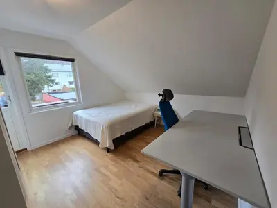 a bedroom with a bed and a desk and a window at 6 Bedroom House in Ålesund