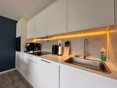 a kitchen with white cabinets and a stainless steel sink at Cozy basement apartment in Ålesund
