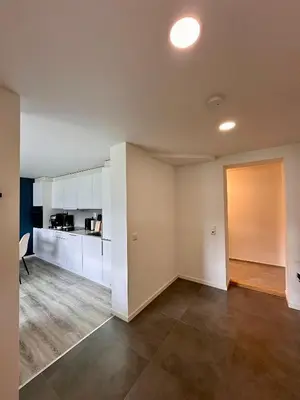 an empty kitchen with white cabinets and a door at Cozy basement apartment in Ålesund