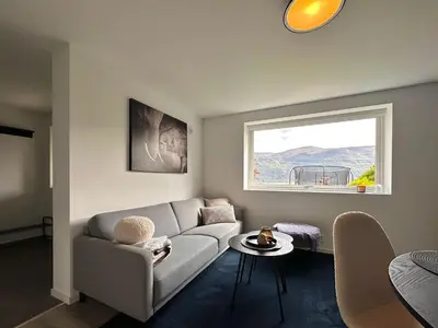 a living room with a couch and a window at Cozy basement apartment in Ålesund