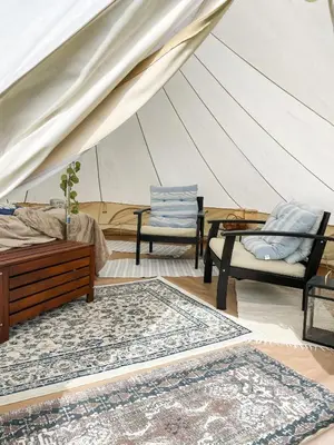 a room with a tent with two chairs and a rug at Glamping Kalhagen in Vangsbygd