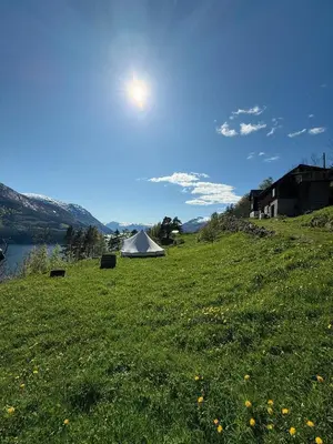 a tent in a field next to a lake at Glamping Kalhagen in Vangsbygd