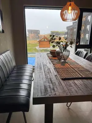 a dining room table with a black leather chair and a table with a tableablish at Helgatunlia - Leilighet 2 in Vossevangen