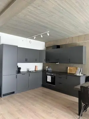 a kitchen with black and white cabinets and a table at Helgatunlia - Leilighet 2 in Vossevangen
