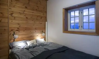 a bedroom with a bed with a wooden wall at Modern Mountain Cabin With Views At Filefjell in Tyinkrysset