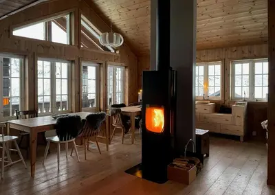 a living room with a fireplace and a table with chairs at Modern Mountain Cabin With Views At Filefjell in Tyinkrysset