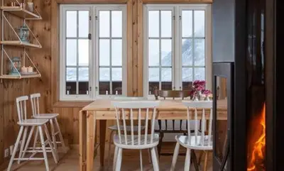 a kitchen with a table and chairs and windows at Modern Mountain Cabin With Views At Filefjell in Tyinkrysset